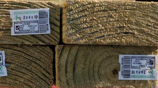 A closeup view of pressure treated lumber with barcode tags stapled to the ends that show Forest Council certification and the lumber dimension: 2x4x10.