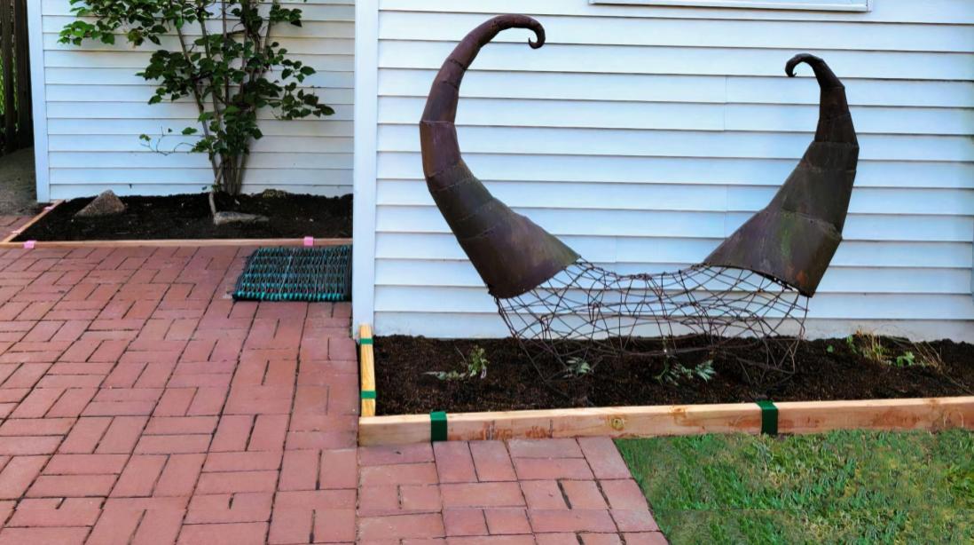 A red brick patio with garden beds edged with 2x4 pressure treated lumber installed with Rose Pink 2xEDGE Staples and Forest Green 2xEDGE Staples.