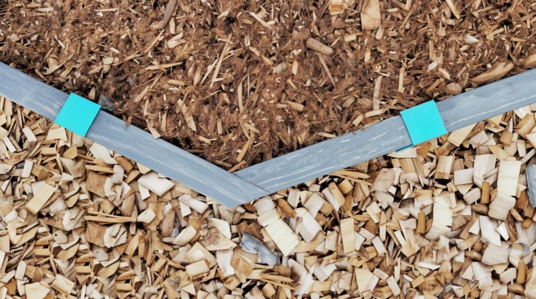 Wood landscape edging stained a dark walnut and installed to the ground with Robins Egg Blue 2xEDGE Staples to separate cedar mulch and wood chips.