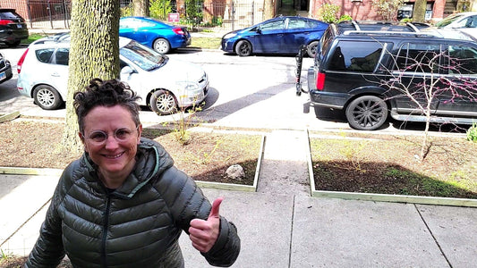 A smiling woman giving her curbside garden landscape edging a "thumbs up".