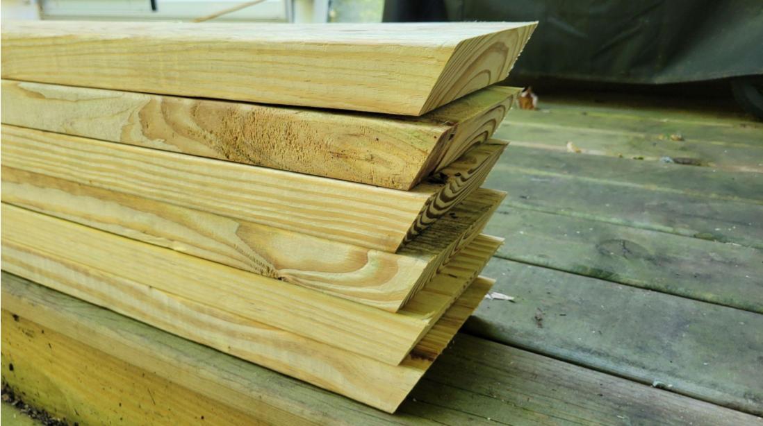 A stack of 2x6 pressure treated lumber with ends cut at an angle in preparation to use as garden edging.
