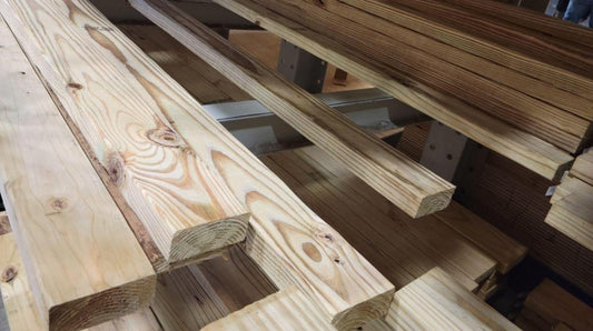 Stacks of 2x4 pressure treated lumber on a shelf.