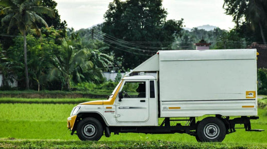 Side view of a delivery truck driving down a road.