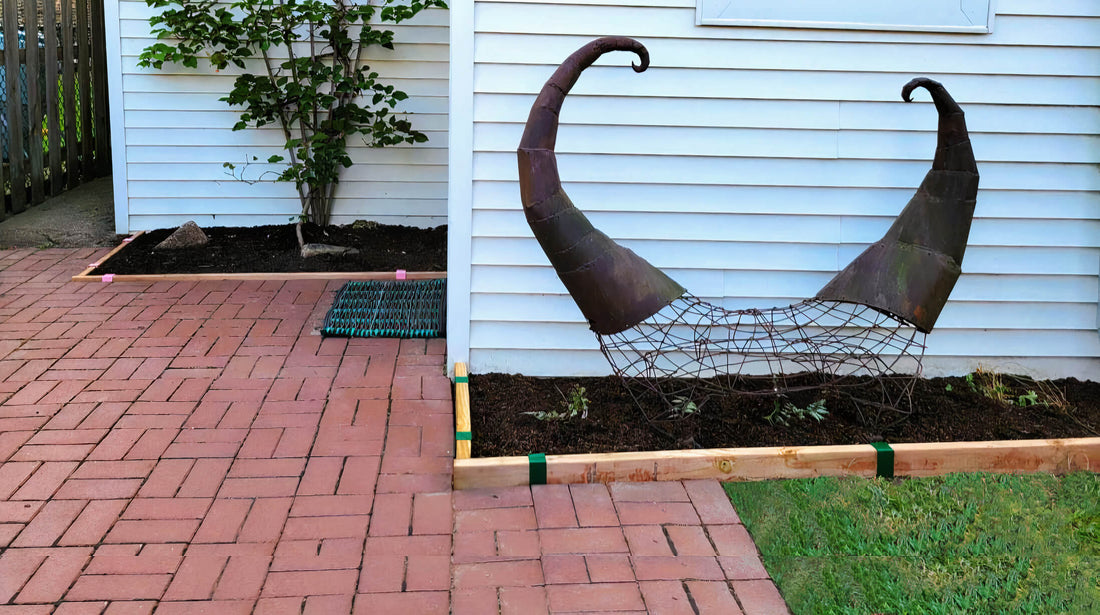 Brick patio with two garden beds, one with a climbing hydrangea the other with a sculpture feature, both edged with two-by (2x) lumber and 2xEDGE Staples.