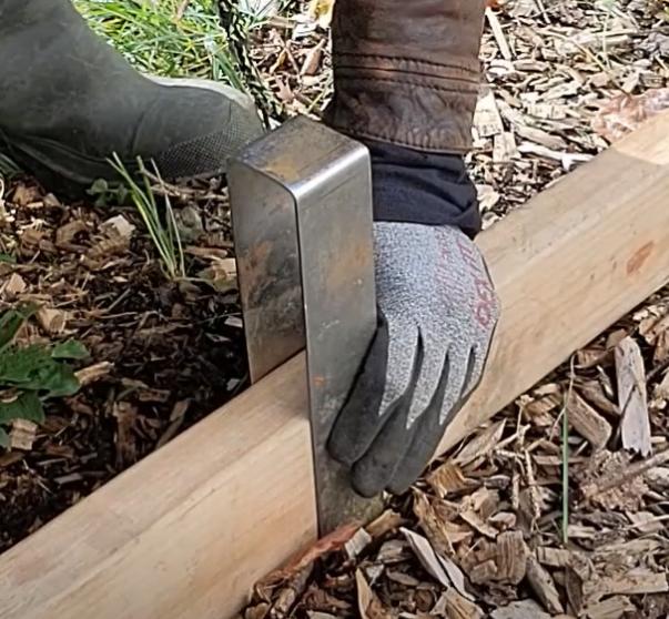 The correct way to grip a 2xEDGE Staple that's been placed over 2x4 lumber with a focus on where to place the fingers.