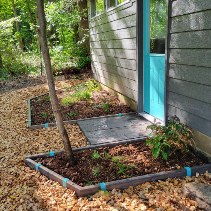 Robins Egg Blue 2xEDGE Staples and 2x4 lumber stained dark walnut create wood garden edging around garden beds at the entryway of an artist studio.