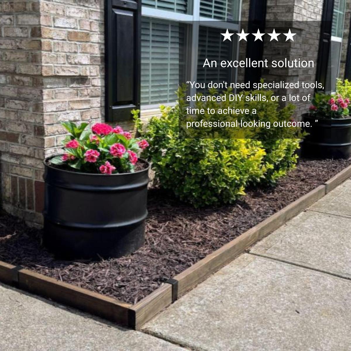 Stained 2x4 lumber edging along a flower bed beside the sidewalk, with a brick house and potted plants.
