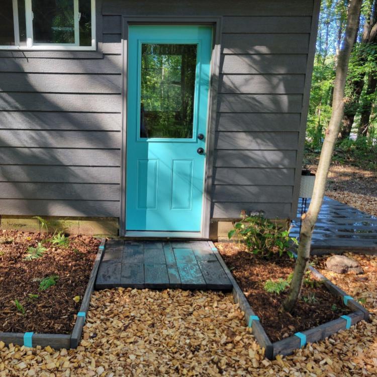 2x4 lumber stained a dark walnut and contrasting Robins Egg Blue 2xEDGE Staples installed as garden bed edging at a front entry walkway.