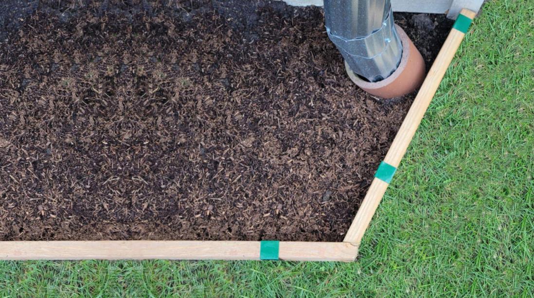 Organic mulch held in place with wood edging that separates a garden bed from a lawn.