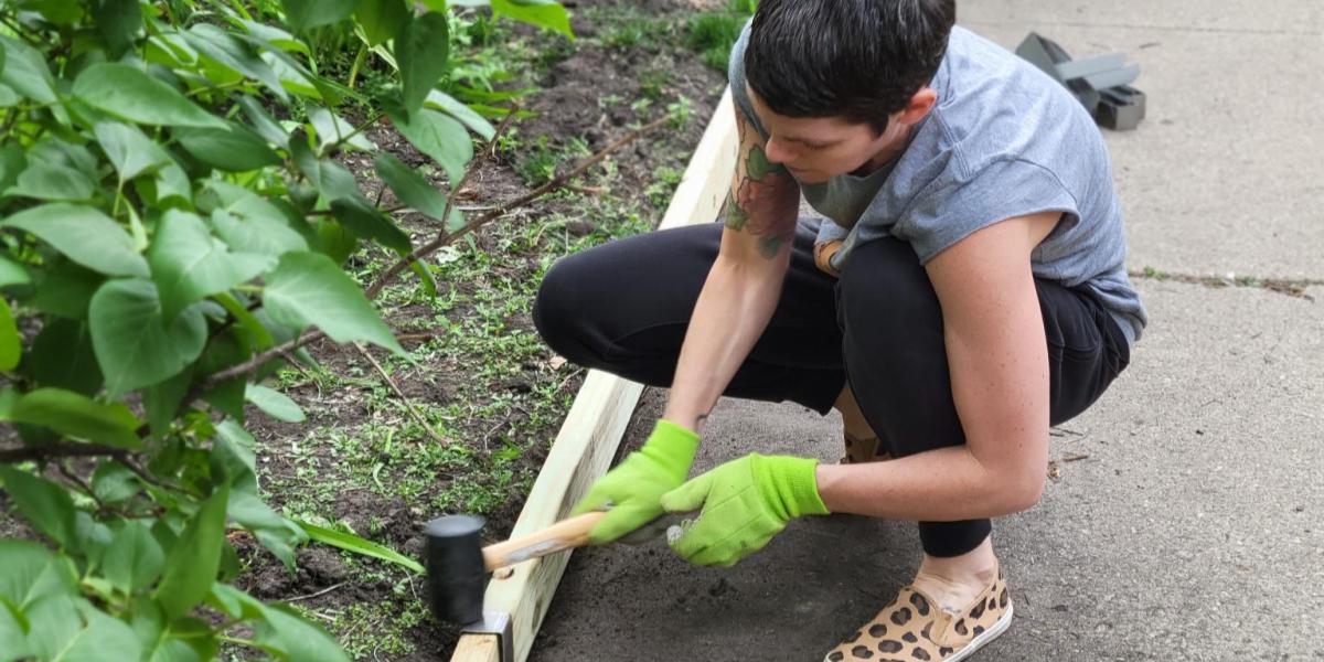 Someone installing a 2xEDGE Staple with a rubber mallet to create sidewalk edging with 2x4 lumber.