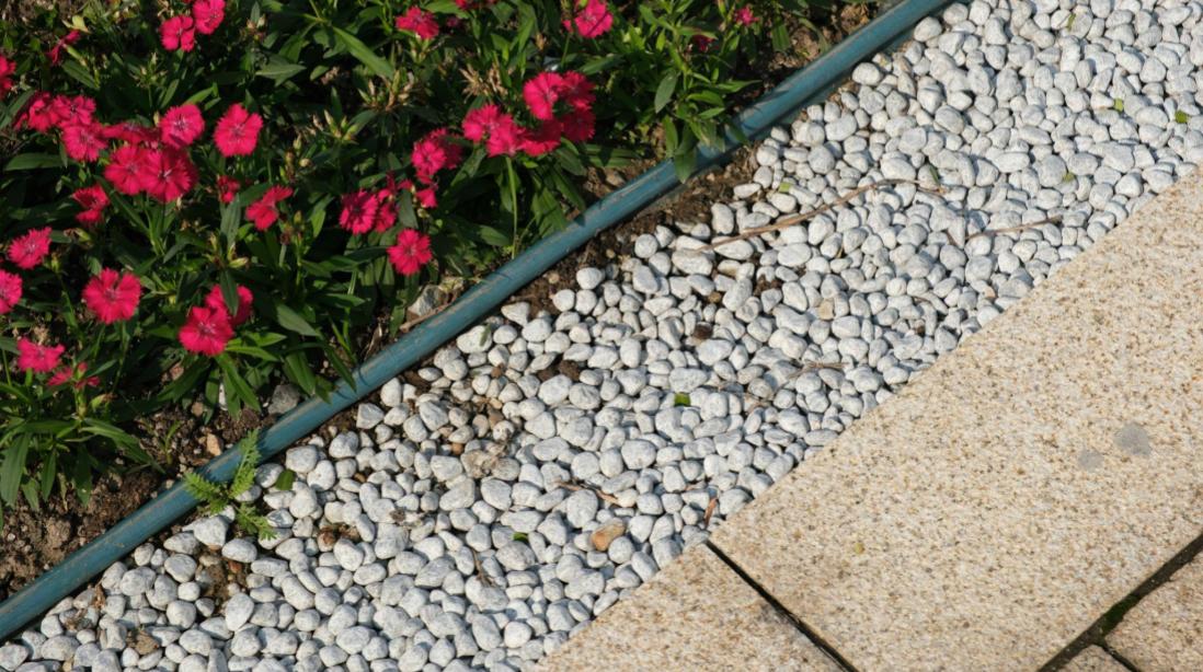 Landscape edging separating a flower bed from gravel with pavers in the foreground. Photo: Reghnall Chow / Unsplash.